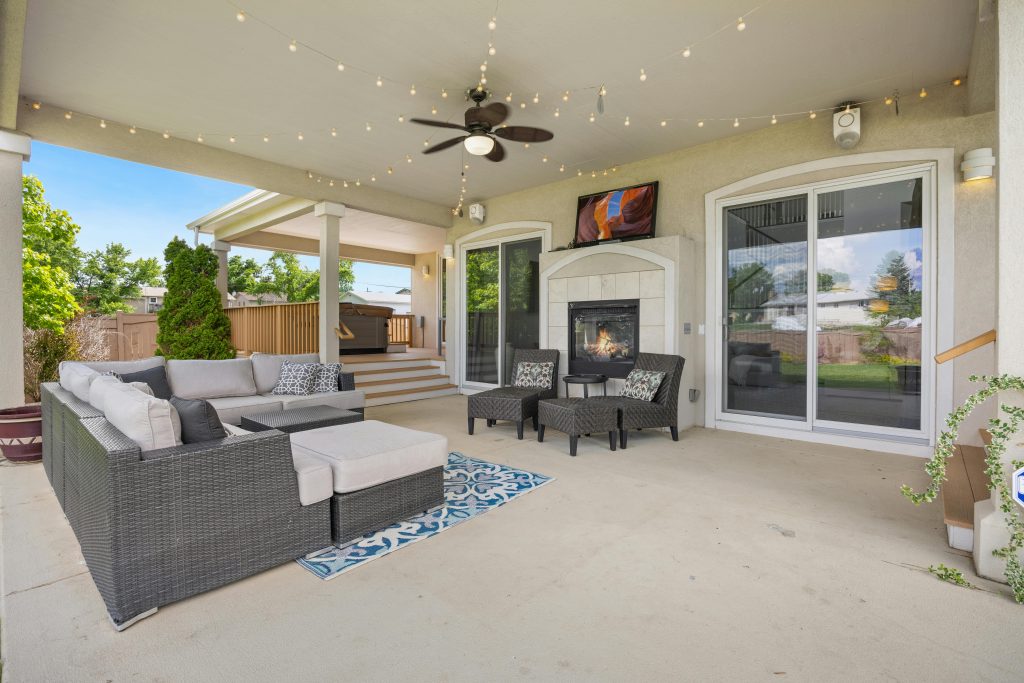 Luxurious outdoor patio featuring a cozy fireplace, modern furniture, and ambient string lights for a perfect relaxation spot.